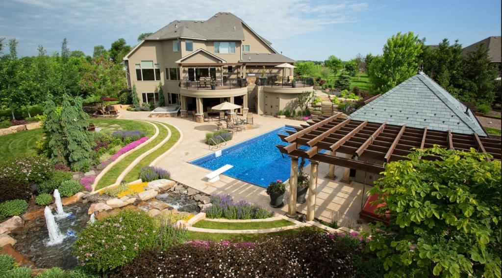 Aerial view of the back of 7250 Jubert Lane with the pool, pergola and landscaped grounds